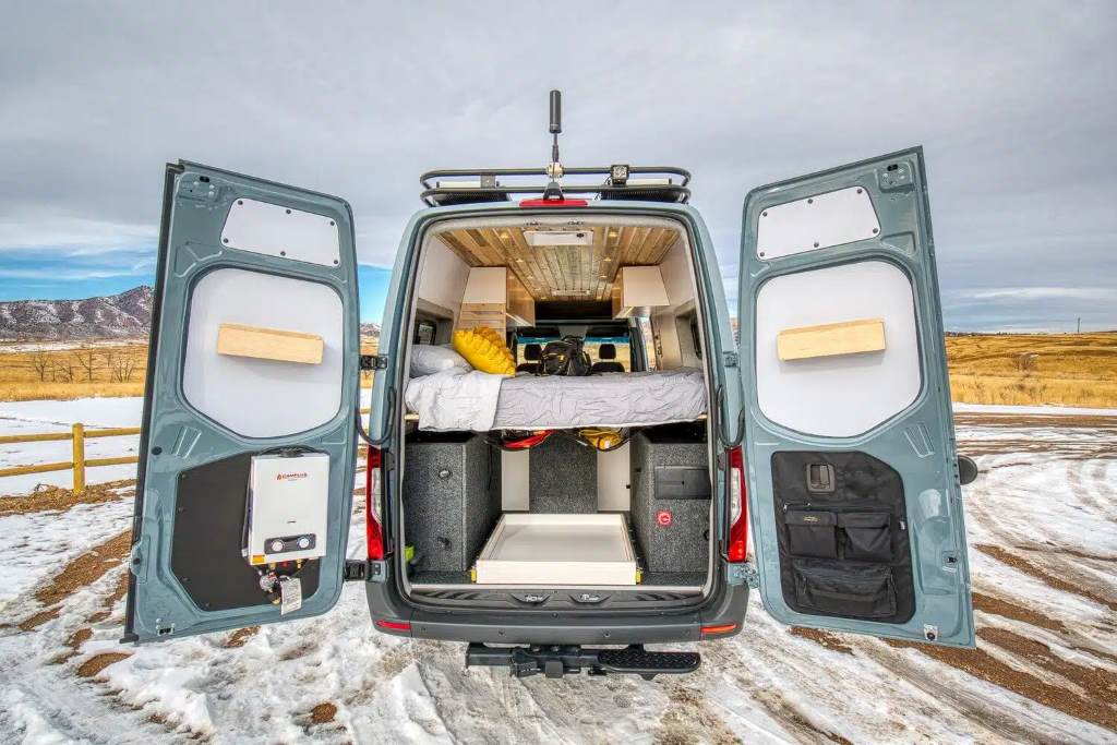A neatly organized day van interior with storage bins and a ceiling cargo net holding camping gear