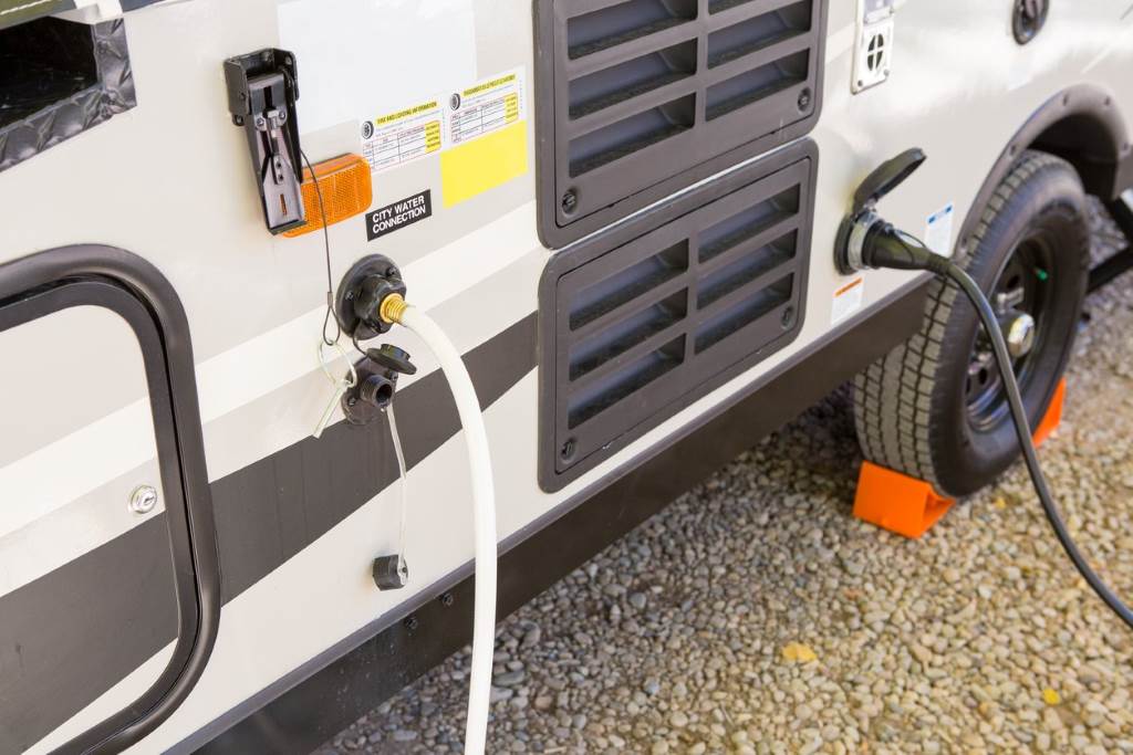 Technician attaching blow out plug to RV city water inlet during winterization process